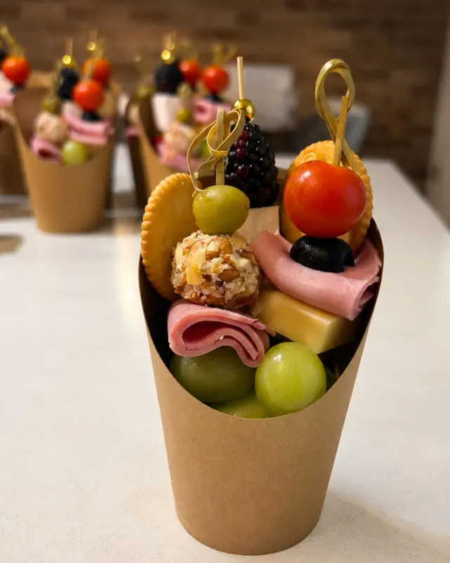 Cono de botana con brocheta de fruta, carnes frías y queso